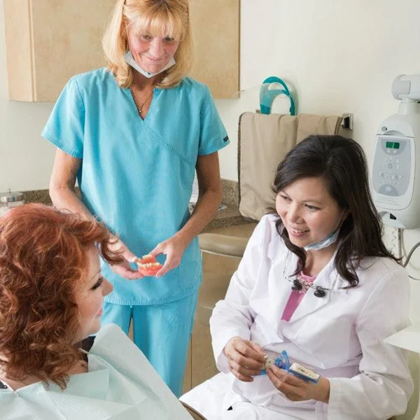 Dr. Tina Le and a dental assistant discussing treatment with a patient
