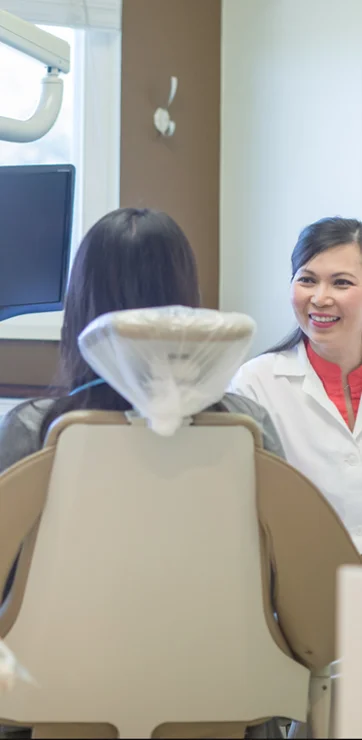 Dr. Tina Le smiling at a patient who sits in a dental exam chair